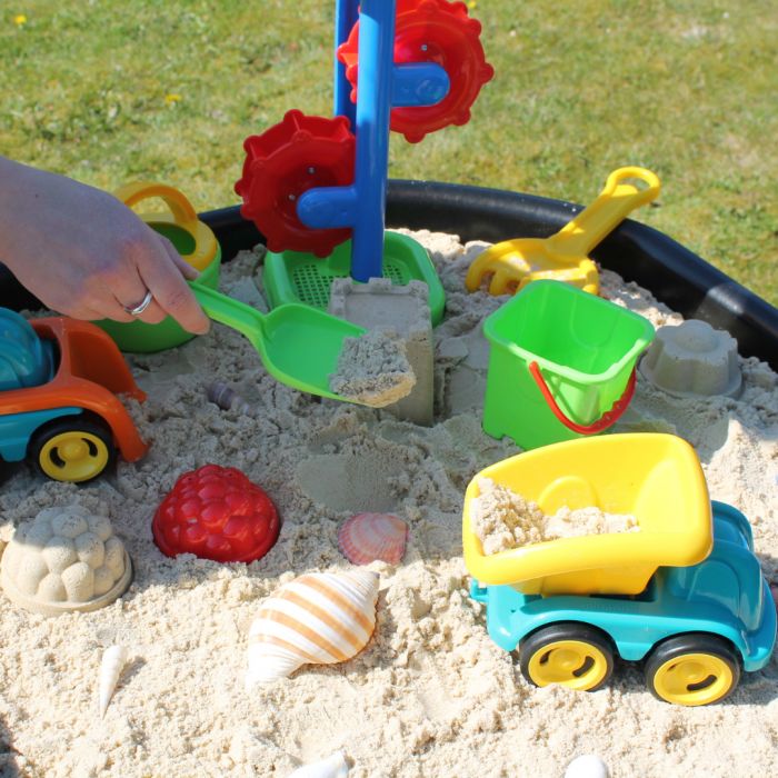 child digging into sand inside of tuff tray