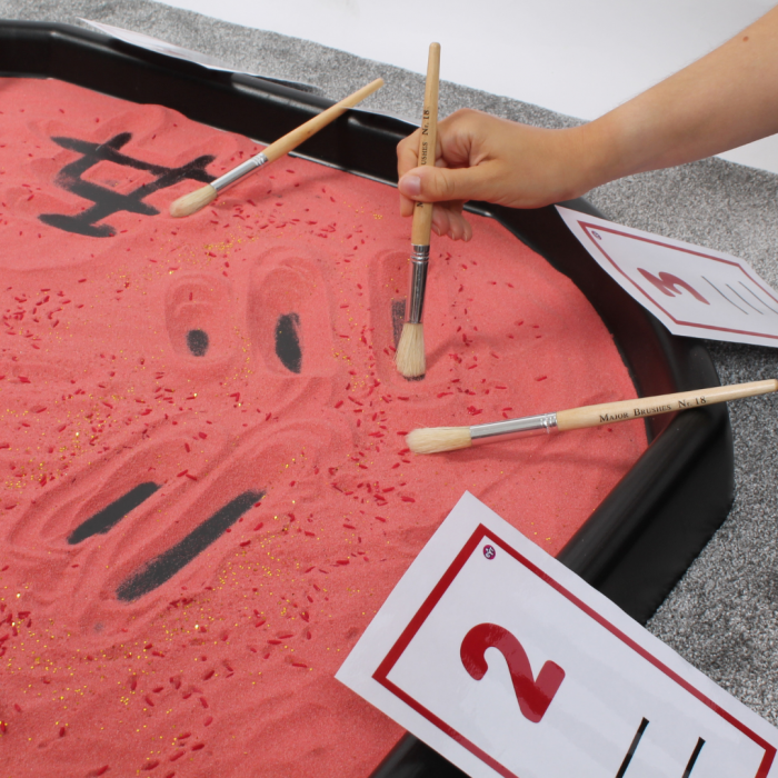 mark making with brushes in red sand